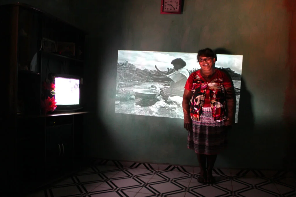 BRA Monte Santo/Sertão de Canudos/Bahia/Brazil 23/03/2016 TWENTY-SEVEN YEARS LATER.Portraits made in Bahia's coutryside, Brazil, where the Canudos War took place 120 years ago. After 27 years, I returned to the region and found some residents who were photographed in 1989 when I took the same path as the Brazilian army's fourth expedition which defeated the Canudos village in 1897.The washerwoman Eleni, 49 years old,  pose for a 1989 photograph when she was only 22 and was washing clothes in rainwater wells in rural Monte Santo.
Back then, the Brazilian Republic was very recent and it took the militaries 4 battles to defeat the village where the people, leaded by Antonio Conselheiro and armed with sticks, knives and shotguns, won the first 3 battles. The people from the village were suffering with starvation and the drought. Slavery had been recently abolished in the country and groups of former slaves wandered through the roads. Without land and job opportunities, they strongly believed in Antonio Conselheiro’s preaching. Since the people demanded not to pay for taxes, the village became a threat to the republican government. Conselheiro was against civil marriage and as a devout man, he said he had been sent by God. To the Bahia’s government, land owners and the Church, these people were seen as rebels who should be eliminated. The fourth expedition was fundamental to defeat the village people. It was a bloody battle: 20,000 village people and 5,000 militaries died.The photographies from the two periods show how the village changed. The return after 27 years enabled meaningful interactions: five people from the first travel were found and could be photographed with their old pictures projected onto them, which was very thrilling for them. Many visual correlations could be seen in the region’s landscape, and that enabled the creation of new color pictures about men, war, myth and the land.