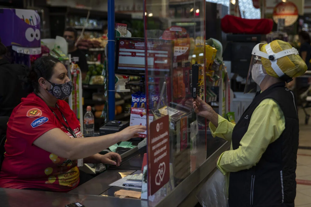 SAO PAULO, SP, 03.08.2020: ENSAIO - COTIDIANO -  NOVO  NORMAL - Ensaio sobre o novo normal no cotidiano de São Paulo, imposto pela pandemia do novo coronavírus e as medidas restritivas de segurança. Na foto, mulher usa EPI em caixa de supermercado Hirota, na Vila Monumento. Mercados tem adotado medidas de proteção como acrílicos nos caixas e uso de máscara obrigatório para conter o avanço do novo coronavírus. (Foto: Mathilde Missioneiro/Folhapress) **EXCLUSIVO FOLHA**